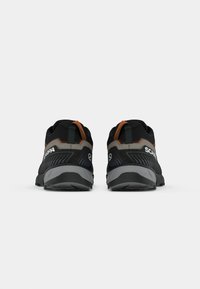 Black hiking shoes with a textured mesh upper, gray rubber soles, and a subtle orange accent on the heel. Features a logo on the side.