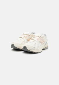 Baskets blanches de sport avec une tige en maille, accents roses et semelle en caoutchouc grise. Présente des lacets, une languette rembourrée et un branding distinctif.