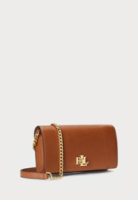 Borsa a tracolla in pelle marrone con un design essenziale, tracolla in catena dorata e logo dorato prominente sul davanti. Texture liscia, forma minimalista.