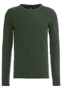 Grön långärmad topp i texturerad tyg, med rund halsringning och åtsittande ärmslut. Liten varumärkesdetalj nära fållen.