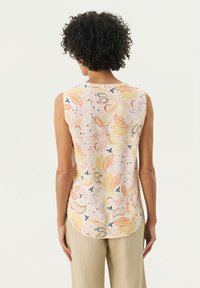 Blouse sans manches avec un motif floral pastel comprenant des éléments jaunes, orange et bleus. Tissu lisse, ourlet arrondi et détails de conception au dos.