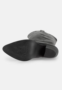 Stivale in pelle nera con punta affusolata, texture liscia e tacco arrotondato. La suola è piatta con un discreto impressivo del logo.