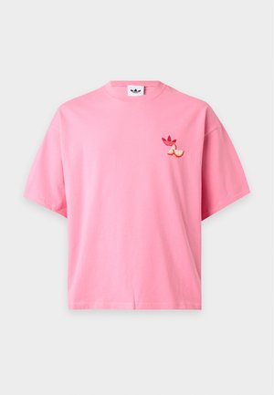 T-shirt rose à manches courtes avec logo trèfle rouge et deux tranches de pamplemousse sur la poitrine gauche, fond uni.