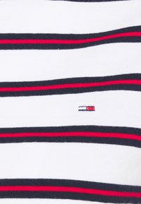 Camisa blanca a rayas con rayas horizontales en azul marino y rojo, textura suave y un pequeño logo bordado en el lado izquierdo.