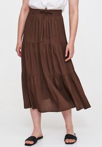 Brąskowa spódnica maxi z lekkiego materiału, z warstwowym krojem, elastycznym pasem w talii z regulowanym sznurkiem oraz zwiewnym fasonem.