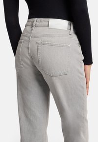 Gray denim pants with a high waist, featuring two back pockets and a white leather brand label at the waistband.