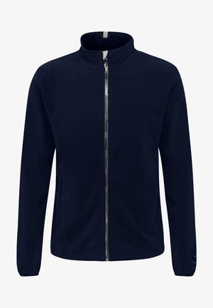 Merinotakk med høy krage, glidelås foran og to sidelommer. Har logo-detaljer på glidelås og mansjetter. Glatt tekstur.