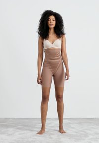 Brune høytlivs shapewear-shorts laget av glatt, elastisk stoff, med mid-thigh lengde og sømløst design.