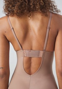 Nude badpak met verstelbare banden, een sleutelgatopening op de rug en een gladde, rekbare stof.