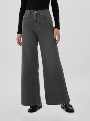 Jeans in denim grigio a gamba larga con vita alta, dotati di tasche frontali e dettagli in metallo rame, abbinati a mocassini neri.
