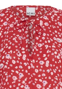 Chemisier floral rouge avec des fleurs roses et violettes, col en trou de serrure et nœud à nouer sous l'étiquette de la marque ICHI.