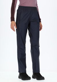 Marineblau wasserfeste Hose mit elastischem Bund, Seitentaschen und glatter Textur, kombiniert mit schwarzen robusten Stiefeln.