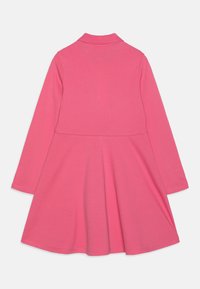 Robe longue rose à manches longues avec un col, présentant un corsage ajusté et une jupe évasée. Fabriquée en tissu lisse et extensible de couleur unie.