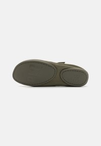 Suela de zapato textil verde con forma redondeada, presenta grabado del logotipo de la marca y tamaño 38. Material suave y flexible con detalles de costura.