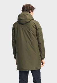 Olivengrøn vandtæt parka med hætte, lange ærmer og lige snit. Har elastiske manchetter og en glat, mat teksturfærdig.