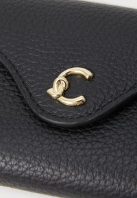 Black leather wallet featuring a textured surface, rounded shape, and a gold-tone clasp detail with intertwined design.