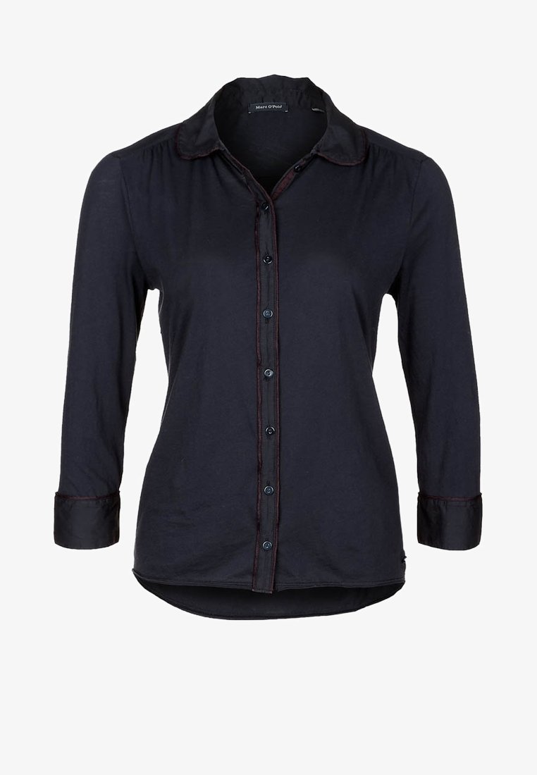 Chemise noire à manches longues, col, sept boutons et un ourlet légèrement arrondi.