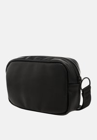Borsa cosmetica rettangolare nera realizzata in materiale testurizzato, con chiusura a zip sulla parte superiore e una tracolla laterale per il trasporto.
