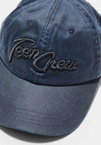 Cappellino blu navy realizzato in materiale morbido, con un logo ricamato "Teen Crew". Visiera curvata con dettagli di cucitura visibili.