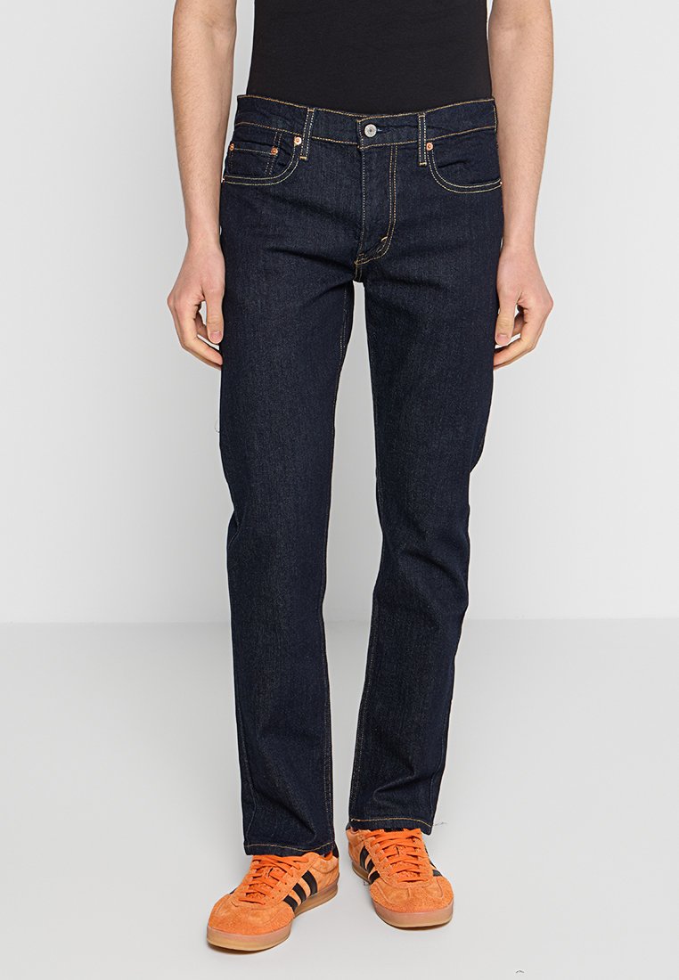 Jeans en denim bleu foncé avec une coupe droite, dotés de cinq poches, de coutures contrastantes et d'une fermeture à glissière avec bouton.