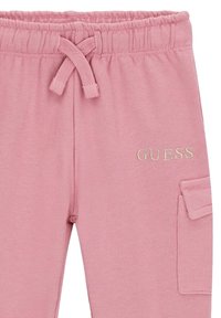 Pantaloni jogger in cotone rosa con vita elastica, coulisse, tasca laterale e logo "GUESS" ricamato in oro. Tessuto morbido e di texture.