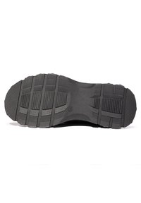 Suela de zapato de goma negra con patrones de dibujo profundos, que presenta ranuras horizontales y verticales para tracción y agarre.