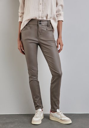 Slimfit bruna byxor i ett slätt, glänsande tyg, med två framfickor och dubbelknäppning, kombinerade med vita sneakers.