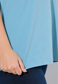 Top azzurro chiaro a maniche corte realizzato in morbido cotone, con una vestibilità rilassata e orlo curvo. Finitura texturizzata, cuciture visibili.