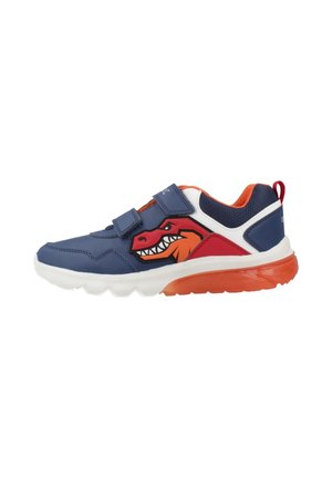 Zapatilla infantil azul marino con detalles en naranja y blanco, gráfico de dinosaurio en el lateral, dos correas de velcro y suela naranja.