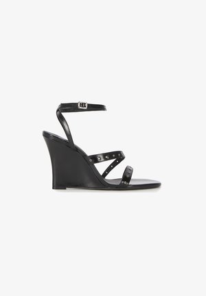 Black wedge sandal with three thin studded straps and an adjustable ankle strap with silver buckle.