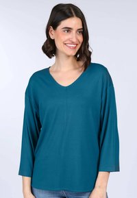 Türkisfarbenes V-Ausschnitt-Oberteil mit langen Ärmeln, aus weichem Stoff gefertigt, mit lockerer Passform und glatter Textur. Ideal für Freizeitkleidung.