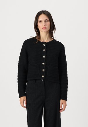 Gilet en tricot noir avec un motif texturé, col rond et six boutons en argent. Il dispose de deux poches avant.