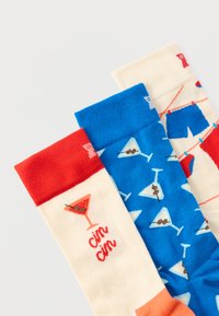 Τρία πολύχρωμα καλτσάκια με σχέδια ποτηριού κοκτέιλ και πλυντηρίου, με κόκκινες, μπλε και κρεμ κορυφές και παιχνιδιάρικα μοτίβα.