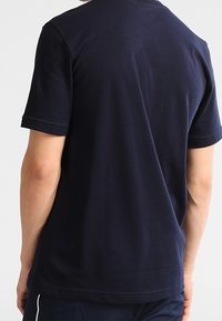 Camiseta de algodón azul marino con mangas cortas y cuello redondo. Textura suave, corte relajado y diseño minimalista, sin patrones ni acentos.