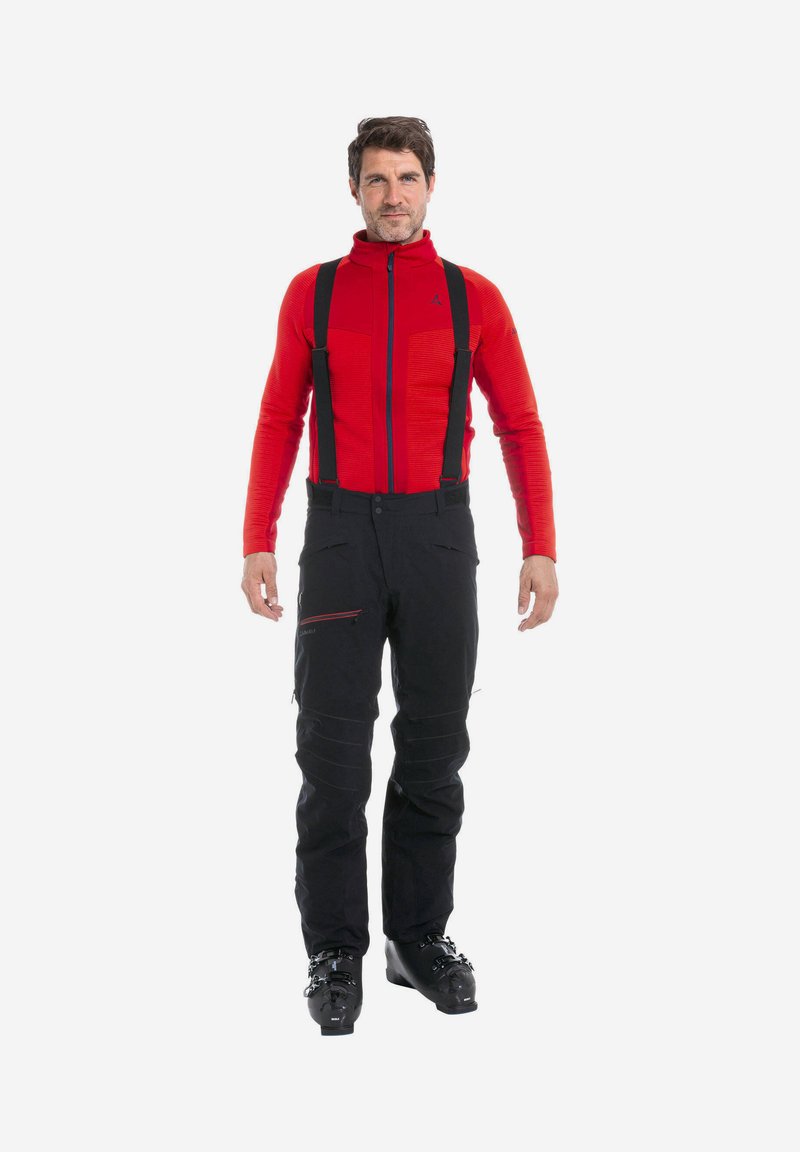 Rode languit top met een gestructureerd patroon, gecombineerd met zwarte skibroek met verstelbare banden en zijritsen. Zwarte skibotten.