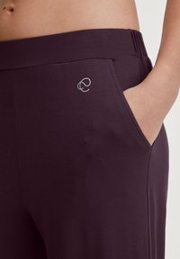 Paarse leggings met een elastische tailleband, zijzakken en een klein reflecterend logo aan de voorkant. Glad, lichtgewicht stof.