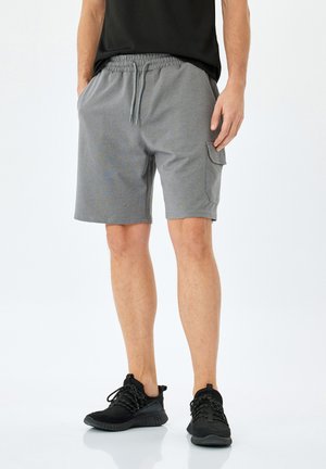 Pantalones cortos activos grises de tela suave, con cintura elástica y cordón, bolsillos laterales y un corte relajado.
