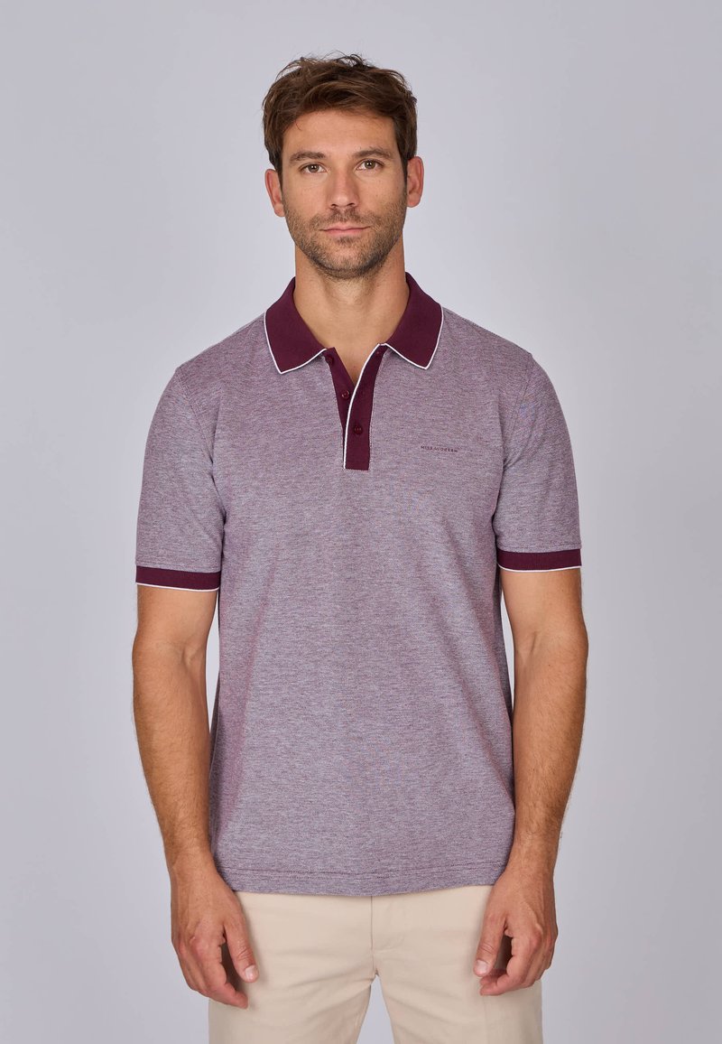 Polo à manches courtes de couleur violet clair avec un col et des poignets rouge foncé, doté de bords blancs contrastants et d'un logo discret sur la poitrine.