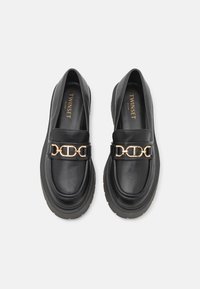 Zwarte leren loafers met een gouden kettingaccent, lage platformzool, gladde textuur en rond toegestane vorm. Merklogo zichtbaar aan de binnenkant.
