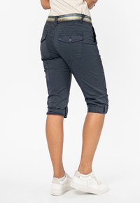 Donkerblauwe capri-broek met opgerolde manchetten, voorzien van achterzakken en een meerkleurige gestreepte tailleband. Glad weefsel.