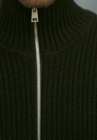 Czarny dzianinowy sweter z wysokim kołnierzem i zamkiem błyskawicznym z przodu, z fakturowanym ściągaczem i kontrastującym srebrnym zamkiem.