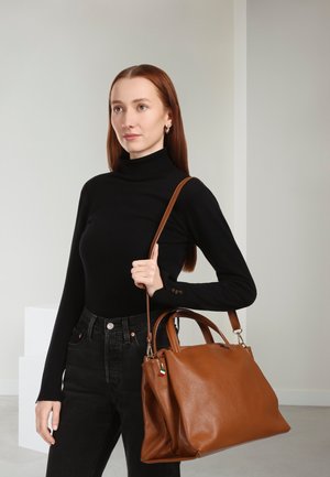 Brown leather handbag with a textured finish, dual top handles, a detachable shoulder strap, and a small colorful tag.