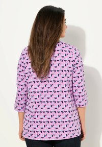Rosa Bluse mit geometrischem Muster in Lila und Marineblau, mit Dreiviertelärmel und einem weichen, strukturierten Stoff.
