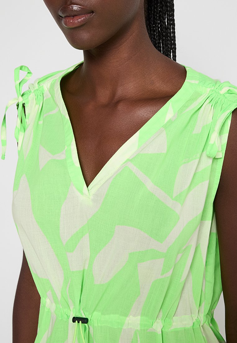 Zielona i biała sukienka w wzory z dekoltem w serek, regulowanymi związkami na ramionach oraz ściągaczem w talii. Lekki materiał.