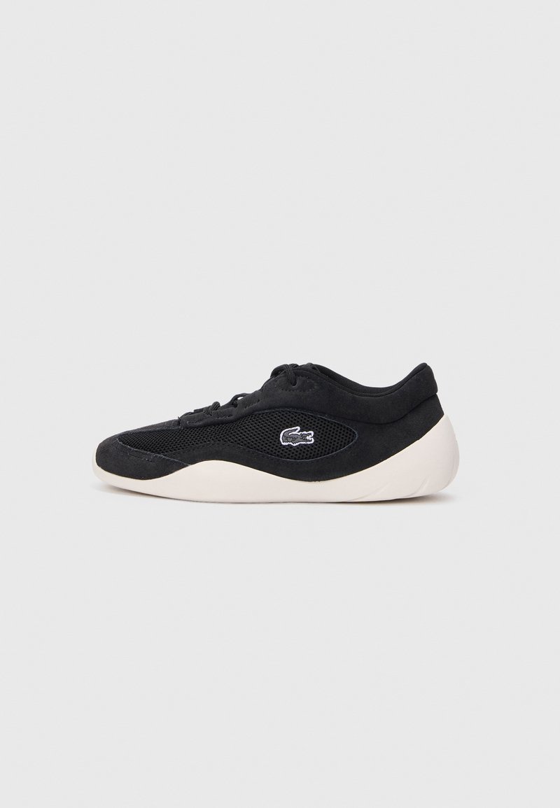 Baskets noires avec côtés en mesh, semelle blanche et petit logo crocodile, présentées de profil sur un fond uni clair.