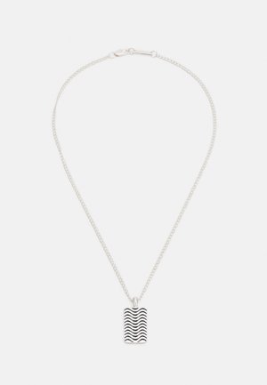 Colar de corrente prateada com um pendente retangular com um padrão de linha preta ondulada. A corrente é delicadamente ligada e ajustável.