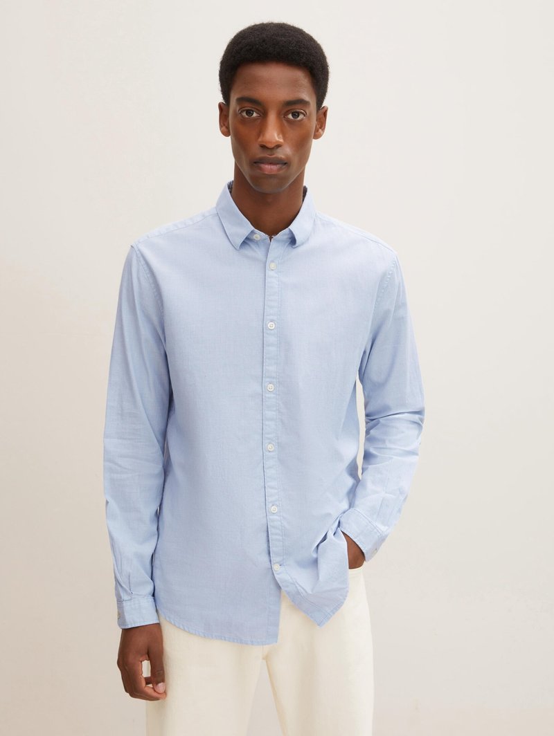 Lichtblauwe button-up shirt gemaakt van ademende stof, met een klassieke kraag en lange mouwen. Glad textuur met een lichte glans.