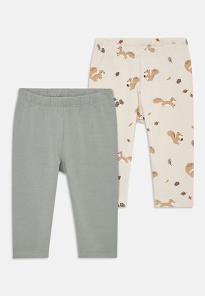 Két pár leggings: az egyik zöld, sima textúrával, a másik krémszínű, mókus- és levélmintával. Mindkettő elasztikus derékrésszel rendelkezik.