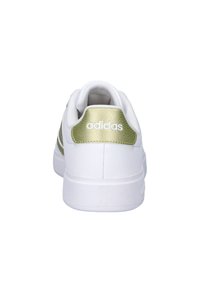Witte sneaker met getextureerde groene accenten bij de hiel en drie witte strepen aan de zijkant. Glad leren materiaal, gevoerde kraag en platte zool.