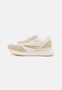 Zapatillas deportivas beige y blancas con una parte superior texturizada, detalles en dorado y una suela acolchada. Presentan un diseño de cordones y materiales en contraste.